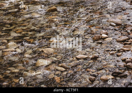 Fließt das Wasser über die Felsen und Steine an einem sonnigen Tag Stockfoto