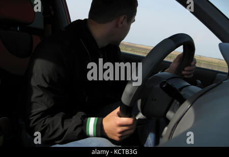 Der Mann am Steuer des Autos schaut aus dem Fenster um. Stockfoto