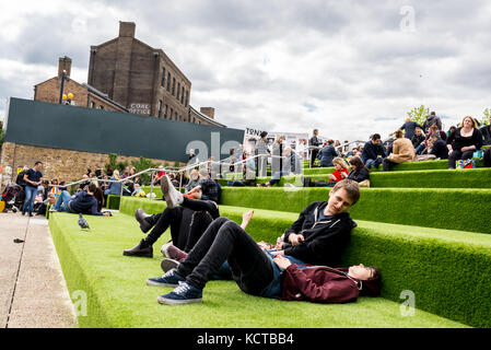 Junge Leute, die den Sommer in den Granary Square Steps genießen. Der Granary Square ist ein öffentlicher Platz am Ufer des Regent’s Canal und das Herz von King’s CR Stockfoto