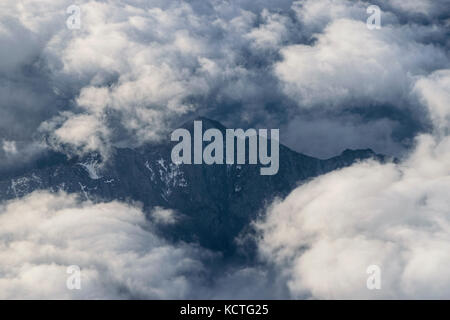 Luftbild des schönen Schnee-Alpen durch graue Wolken umgeben mit einer Kappe bedeckt Stockfoto