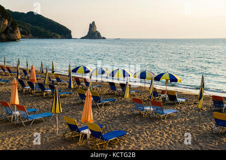 Regenschirme und Sonnenschirme am Strand neben Ionische Meer bei Sonnenuntergang Stockfoto