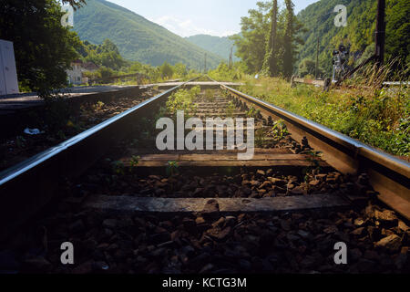 Low Angle View von Bahnstrecken mit abnehmender Perspektive, die zu üppigen Grün der Berge Stockfoto