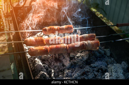 Würstchen eingewickelt in Speck auf den Grill. Schließen. Selektive konzentrieren. Stockfoto