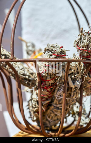 Metallkorb hält handgefertigte smudgesticks mit roten und weissen String aufgewickelt Stockfoto