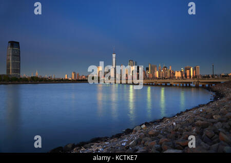 Die Nachtansicht von Goldman Sachs & Co; Tower in Jersey City und Lower Manhattan mit North Cove im Liberty State Park im Vordergrund. New Jersey, USA Stockfoto