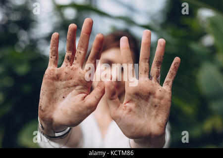 In der Nähe der weiblichen Gärtner ihrer schmutzigen Hände sichtbar mit Boden und Erde im Gewächshaus. Frau nach Garten- und Landschaftsbau in der Gärtnerei. Stockfoto