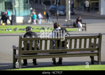 Auf einer Bank sitzen und das Leben von Touristen beobachten, George Square Glasgow Stockfoto