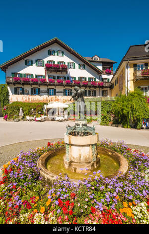 St. Gilgen, Österreich - 24. August 2016: Statue des Jungen Wolfgang Amadeus Mozart und ein berühmtes Hotel "Gasthof zur Post" auf dem Mozartplatz. Stockfoto