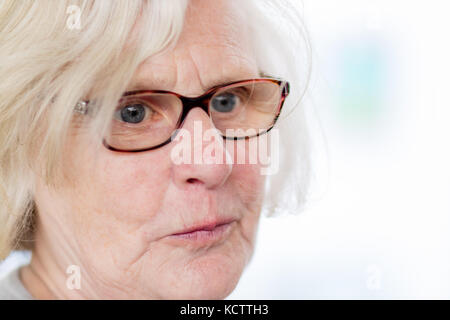 Eine ältere Dame Brillen tragen, ihre Lippen schürzte sich etwas weg von der Kamera. Stockfoto