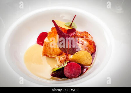 Hummer mit Dashi-Butter, geräucherte Rote Bete und Lachskaviar ist der dritte Gang beim Galadinner des mit einem Michelin-Stern ausgezeichneten Kochs Nick Bril am 26. Februar 2017, Teil des 21. Rheingau Gourmet & Wein Festivals im Hotel und Restaurant Kronenschlösschen in Hattenheim, Eltville am Rhein, Hessen, Deutschland. Hummerstücke, orangefarbener Lachsröucher, Rote-Bete-Scheiben, ein rotes Blatt und zwei Chips ruhen in einer hellen Buttersauce. Er wird serviert mit 2013 Battenfeld-Spanier Mölsheim Riesling Late Release vom Gut Battenfeld-Spanier. Bril ist Küchenchef des The Jane in Antwerpen, Belgien. Er eröffnete es mit Sergio Her Stockfoto