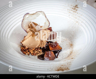 Ein Gourmet-Gericht aus einer hellbraunen Sahne-Quenelle, einem Knusper mit violetter Kante, dunkelrot glasierten Würfeln und knusprigen Lagen auf einem weißen gerippten Teller beim Galadinner "Level Null" (Nullniveau) im Hotel und Restaurant Kronenschlösschen in Hattenheim, Eltville am Rhein, Hessen, Deutschland. Dunkle Sauce umgibt die Würfel. Leichte Gewürzstaub liegt am Rand des Tellers. Das Galadinner "Level Null" (Nullniveau) am Abend des 1. März 2017 ist Teil des 21. Rheingau Gourmet & Wein Festivals. Patissiers Andy Vorbusch (Hotel The Dolder Grand, Zürich) und René Frank (CODA Dessert Bar, Berlin) servieren ein fünf Stockfoto