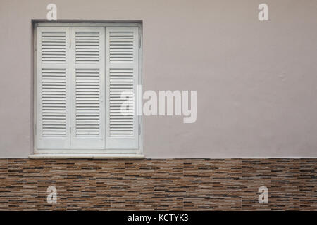 Weiß geschlossene Fenster in der Hauswand, Details der Wand Dekoration und alten Stil Jalousien. Stockfoto