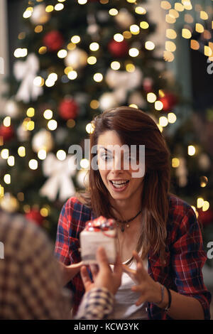 Sehr überrascht und neugierig Frau empfangen Weihnachtsgeschenk von ihrem Mann Stockfoto