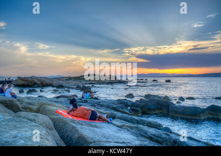 HDR-Bild von Menschen gerade der Sonnenuntergang über Felsen im Meer auf der spanischen Insel Tabarca Stockfoto