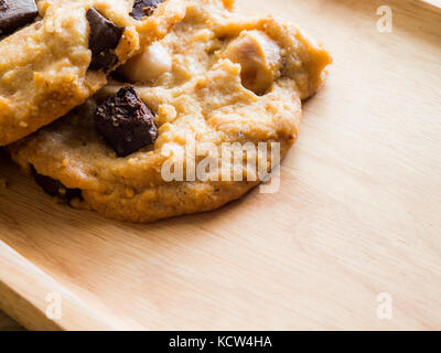 Schließen cookies mit Schokolade und Macadamianüssen. Auf einer hölzernen Platte positioniert. Kaffee Brake Concept. Stockfoto