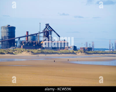 Ein paar Leute am Strand Coatham Redcar an einem Herbsttag, mit der mittlerweile verlassenen Stahlwerk darüber hinaus. Stockfoto