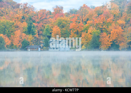 Nebel am Hufeisensee im Herbst mit Häuschen, in der Nähe von Parry Sound, Ontario, Kanada Stockfoto