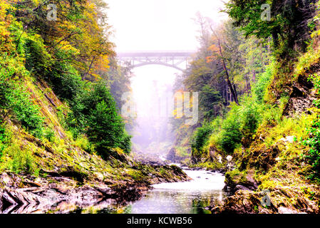 Eine Brücke überspannt die Lücke zwischen einer Schlucht in Vermont an einem nebligen Morgen Stockfoto