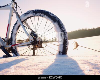 Mountainbike Urlaub im Pulverschnee. verloren weg in tiefe Schneeverwehungen. Hinterrad detail. Schneeflocken schmelzen in dunklen off road Reifen. Winterwetter in den Stockfoto