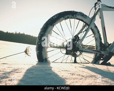 Mountainbike Urlaub im Pulverschnee. verloren weg in tiefe Schneeverwehungen. Hinterrad detail. Schneeflocken schmelzen in dunklen off road Reifen. Winterwetter in den Stockfoto