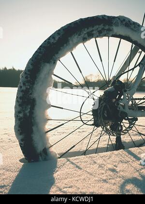 Mountainbike Urlaub im Pulverschnee. verloren weg in tiefe Schneeverwehungen. Hinterrad detail. Schneeflocken schmelzen in dunklen off road Reifen. Winterwetter in den Stockfoto