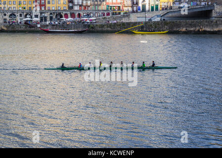 Ruderer in einer gecoxten acht, ein Ruderboot auf dem Fluss Douro, das von der Stadt Vila Nova de Gaia, Portugal, aus gesehen wird. Porto Stadt im Hintergrund Stockfoto