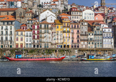 Reihe von Gebäuden am Douro-Ufer in Porto City, Portugal. Blick auf touristische Kreuzfahrtschiffe Stockfoto