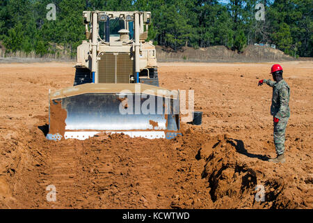 U.s. Army Staff Sgt. Edwin Williams, South Carolina Army National Guard, 218 Führung regiment Ausbilder, die Richtung zu einem raupenschlepper Bediener an mccrady Training Center in Eastover, South Carolina, Feb. 26, 2017 als Teil der horizontalen Bauingenieur Umgliederung Kurs, Soldaten in der manuvering der Traktor für eine Vielzahl von Aufgaben, einschließlich flacher Boden Grabenherstellung zu beherrschen, eine defensive formation Panzer auf dem Schlachtfeld zu verbergen. (U.s. Army National Guard Foto von Sgt. Brian Calhoun, 108 öffentliche Angelegenheiten Abteilung) Stockfoto