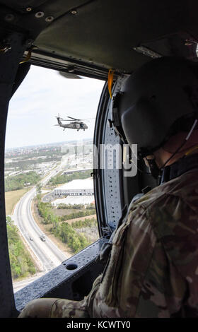 Us-Armee Sgt. dustin Keenan, Abteilung 1, Charlie Co., 2-238 allgemeine Unterstützung aviation Battalion, South Carolina Army National Guard, dient als der Flug medic auf einem UH-60 Blackhawk, fliegen neben Georgia und Louisiana Flugzeuge, duringu. s. Armee Sgt. David roupe, loslösung 1, Charlie Co., 2-238 allgemeine Unterstützung aviation Battalion, South Carolina Army National Guard, unterstützt mock Umsiedler auf ein UH-60 Black Hawk, fliegen neben Georgia und Louisiana Flugzeuge, während eines Hurrikans evakuierungsübung als Teil des wachsamen Schutz 17 in der Gegend von Savannah, Georgia, 29. März wachsam Guard 17. Stockfoto