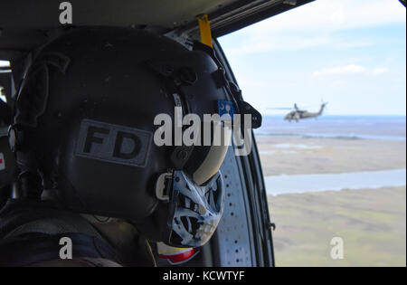 Us-Armee Sgt. David roupe, loslösung 1, Charlie Co., 2-238 allgemeine Unterstützung aviation Battalion, South Carolina Army National Guard, dient als Mannschaft Leiter auf ein UH-60 Black Hawk, fliegen neben Georgia und Louisiana Flugzeuge, während der US-Armee Sgt. David roupe, loslösung 1, Charlie Co., 2-238 allgemeine Unterstützung aviation Battalion, South Carolina Army National Guard, unterstützt mock Umsiedler auf ein UH-60 Black Hawk, fliegen neben Georgia und Louisiana Flugzeuge, während eines Hurrikans evakuierungsübung als Teil des wachsamen Schutz 17 in der Gegend von Savannah, Georgia, 29. März wachsam guard17 ist ein Stockfoto