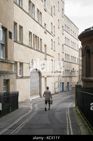 Rückseite der Mann in Shorts tragen Kunststoff Tragetasche und gehen hinunter mitten in Back Street im Stadtzentrum, Badewanne, Großbritannien Stockfoto