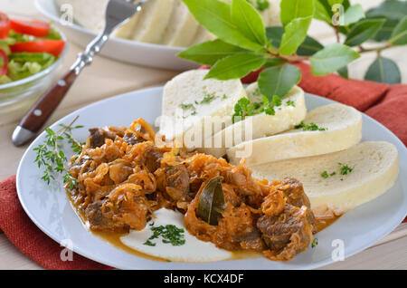 Typisch ungarisches Gulasch (Schwein und Rind) mit marinierten Weißkohl (Sauerkraut) und Knödel in eine Serviette Stockfoto