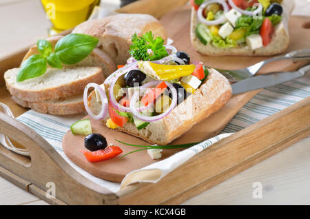 Köstlichen griechischen Bauernsalat mit Feta auf ciabatta Brot, serviert auf einem alten Holz- fach Stockfoto