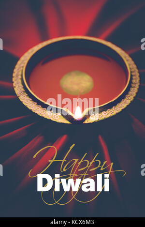 Happy diwali Grußkarte - große beleuchtete Diwali diya oder Ton Lampe über satin Tuch erstellen strahlen Effekt in Tuch, stimmungsvolle Beleuchtung, selektive Stockfoto