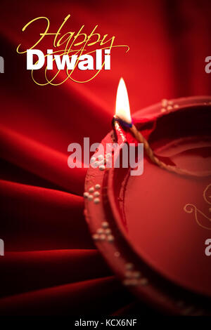 Happy diwali Grußkarte - große beleuchtete Diwali diya oder Ton Lampe über satin Tuch erstellen strahlen Effekt in Tuch, stimmungsvolle Beleuchtung, selektive Stockfoto