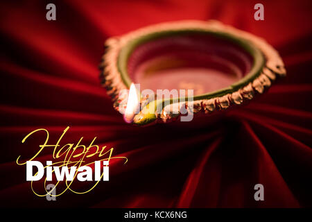 Happy diwali Grußkarte - große beleuchtete Diwali diya oder Ton Lampe über satin Tuch erstellen strahlen Effekt in Tuch, stimmungsvolle Beleuchtung, selektive Stockfoto