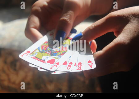 Weibliche Hände mit blauen Fingernägel Verbreitung Packung mit blauen Karten auf Holztisch. Stockfoto