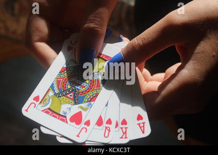 Weibliche Hände mit blauen Fingernägel Verbreitung Packung mit blauen Karten auf Holztisch. Stockfoto