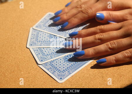 Weibliche Hände mit blauen Fingernägel Verbreitung Packung mit blauen Karten auf Holztisch. Stockfoto