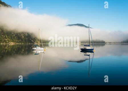 Nebel, Berge, Segelbooten und Yachten in der Morgensonne in die ruhige Oberfläche des Sees im Herbst am Achensee, Tirol, Österreich Stockfoto