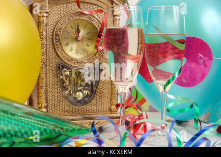 Tischuhr mit fast Mitternacht, Luftschlangen, Luftballons, und zwei Gläser Champagner Stockfoto