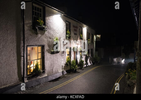 Walker vorbei Golden Rule Pub in der Nacht mit beleuchteten Schild, Kirstone Pass Road, Ambleside, Lake District National Park, Großbritannien Stockfoto