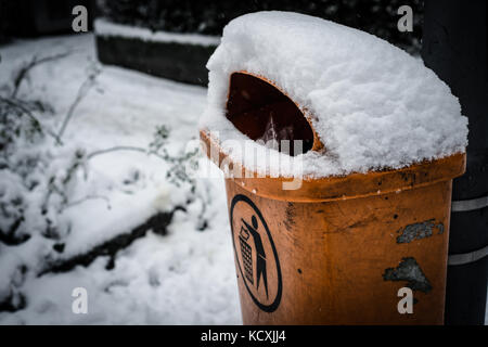 Dirty orange trashcan Müll Mülleimer im Winter mit Schnee bedeckt Stockfoto