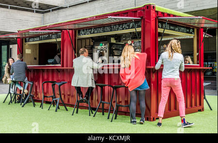 Die Leute trinken an einem Wein und Sangria Bar, aus einer umgebauten Container und rot lackiert. Draußen auf der South Bank, London, England, UK. Stockfoto