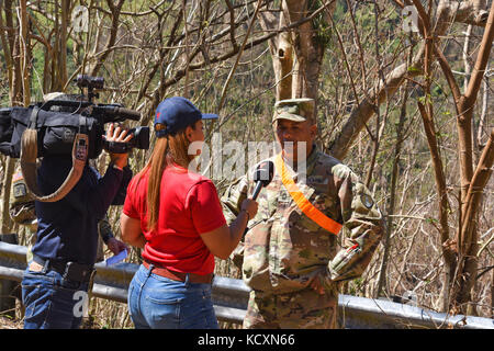 Us-Armee finden Master Sgt. Wigber Torres, allgemeine Ingenieur Supervisor, 471St Co., 448Th Eng. Bn., Der, der das Clearing von lokalen Straße 128, reagiert auf Fragen von einem lokalen TV-Reporter, in der Nähe von Ponce, Puerto Rico, 4. Oktober 2017. Torres ist von Juanadea, Puerto Rico und ist ein Teil der Gemeinschaft, er ist einer von vielen US-Armee finden Soldaten, die hier auf Wunsch von lokalen Beamten unsere Freunde und Nachbarn zu helfen. (U.S. Armee finden Foto von Sgt. Edgar Valdez) Stockfoto