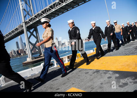 Us-Marines und Navy Sailors "Mann der Schienen" an Bord der USS Essex LHD2 während der Parade der Schiffe während San Francisco Fleet Week 6 Okt., 2017. San Francisco Fleet Week ist eine Möglichkeit für die amerikanische Öffentlichkeit ihre Marine Corps, Navy und der Coast Guard Teams zu treffen und America's Meer Dienstleistungen Erfahrung. Flotte Woche Marineangehörigen, Ausstattung, Technik und Funktionen markieren, mit einem Schwerpunkt auf humanitäre Hilfe und Katastrophenhilfe. (U.S. Marine Corps Foto von Sgt. Rodion Zabolotniy) Stockfoto