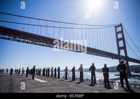 Us-Marines und Navy Sailors "Mann der Schienen" an Bord der USS Essex LHD2 während der Parade der Schiffe während San Francisco Fleet Week 6 Okt., 2017. San Francisco Fleet Week ist eine Möglichkeit für die amerikanische Öffentlichkeit ihre Marine Corps, Navy und der Coast Guard Teams zu treffen und America's Meer Dienstleistungen Erfahrung. Flotte Woche Marineangehörigen, Ausstattung, Technik und Funktionen markieren, mit einem Schwerpunkt auf humanitäre Hilfe und Katastrophenhilfe. (U.S. Marine Corps Foto von Sgt. Rodion Zabolotniy) Stockfoto