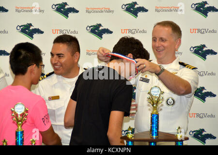 HARLINGEN, Texas - (Okt. 2010) 6, 2017) Naval Aviator Cmdr. Jeffrey Reynolds, kommandierender Offizier, Marine-Einziehende Bezirk San Antonio, von Mercedes, Texas verbunden, native Lt.Cmdr. Artemio Trevino zum Navy Operational Support Center-Harlingen zugeordnet, Auszeichnungen Platz 3 Medaillen Mitglieder der Akademie der Wissenschaften von South Texas während der US-Navy zu Team - geförderte SeaPerch Herausforderung Konkurrenz an den Harlingen Aquatic Center gehalten während der 2017 Hispanic Engineering, Woche für Wissenschaft und Technologie (HESTEC). 35 High School Mannschaften in die Veranstaltung, die von einem Unterwasser Hindernisparcours bestand konkurrierten, ein Stockfoto