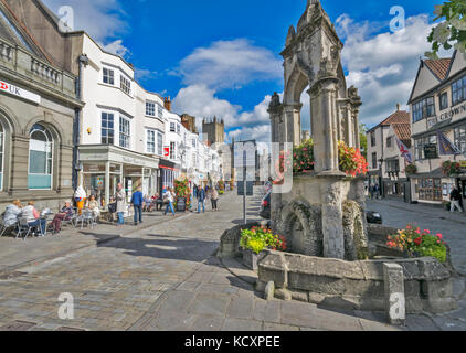 WELLS SOMERSET ENGLAND DER HAUPTSTRASSE, DIE ZU DER KATHEDRALE UND ALTEN BRUNNEN MIT BLUMEN Stockfoto