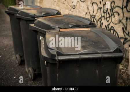 Vier schwarze Abfalleimer Mülleimer auf dem Bürgersteig Stockfoto